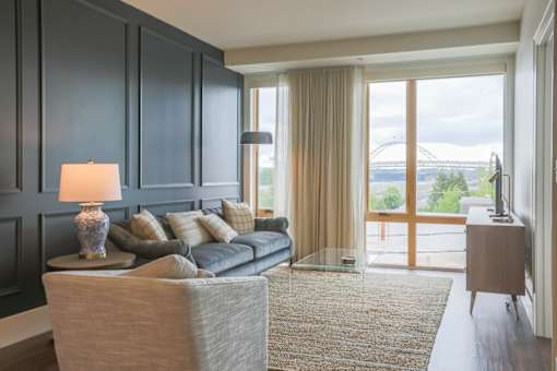 A modern living room with a grey couch and a glass door leading to a balcony.