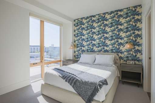 A bedroom with a large bed and a floral wallpaper.