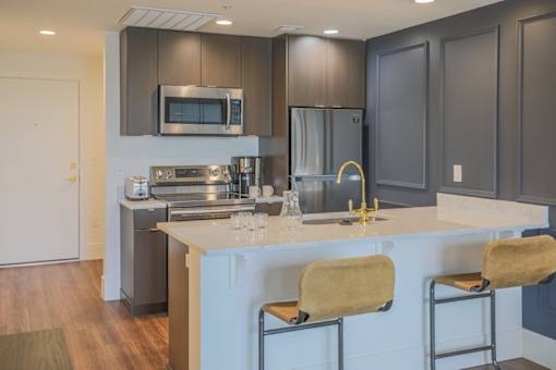 A modern kitchen with a white countertop and stainless steel appliances.