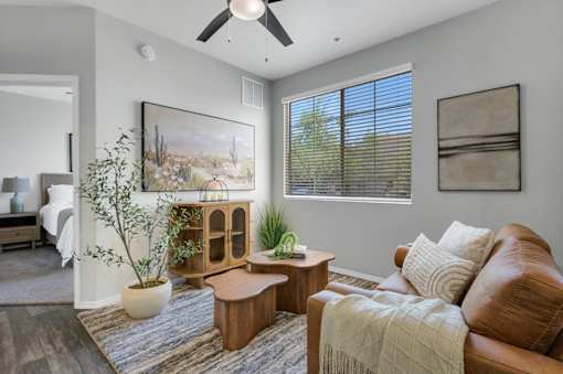 A living room with a brown leather couch, a wooden coffee table, and a painting on the wall.