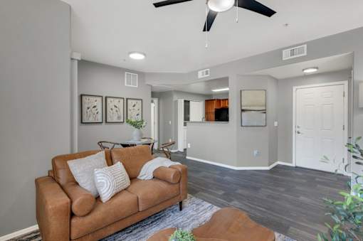 A living room with a brown couch and a ceiling fan.