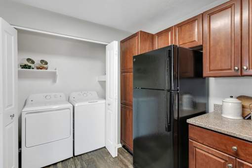 A black refrigerator is in a kitchen with wooden cabinets.