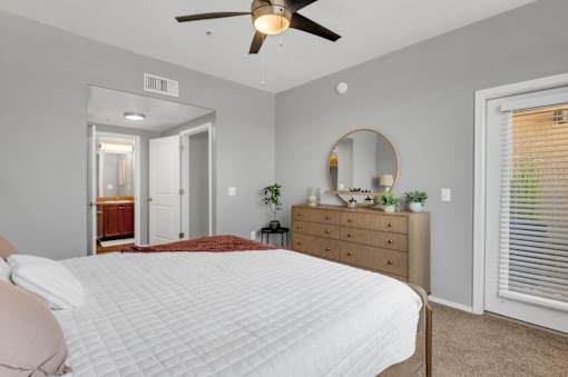 A bedroom with a large bed, a dresser, and a mirror.