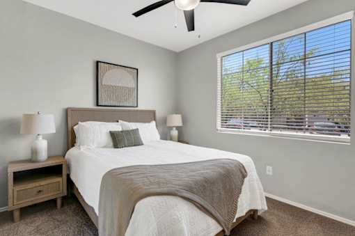 A bedroom with a large bed and a ceiling fan.