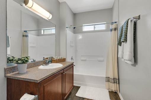 A bathroom with a brown vanity and a white bathtub.
