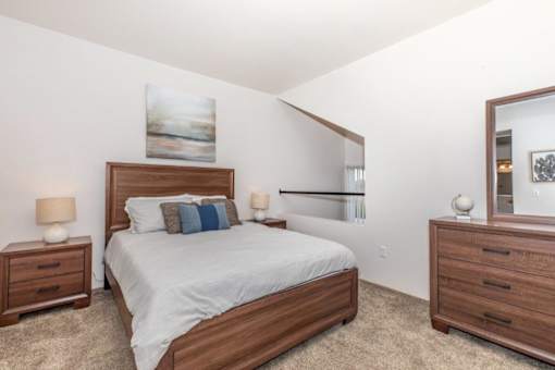 A bedroom with a bed, nightstands, and a mirror.