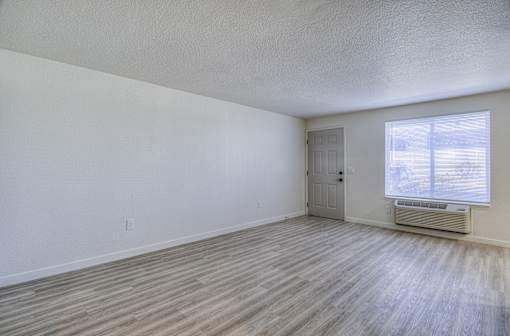 Oasis at 2600 the spacious living room of an apartment with wood flooring and a door to a