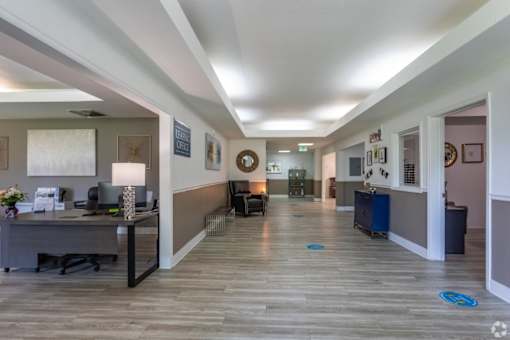 A hallway with a desk and chairs on the left and a doorway on the right.
