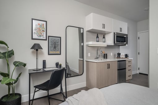 a bedroom with a bed and a desk with a mirror in front of it and a kitchen