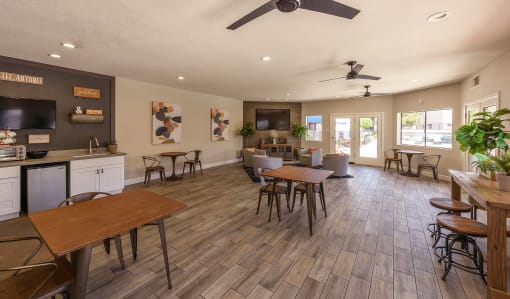a community room with tables and chairs and a kitchen and a tv