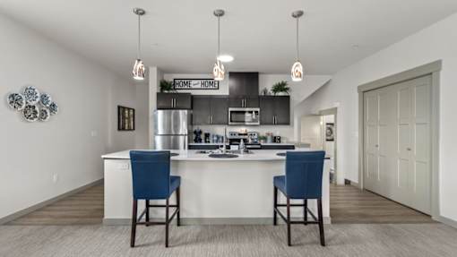 A kitchen with a white counter and blue chairs.