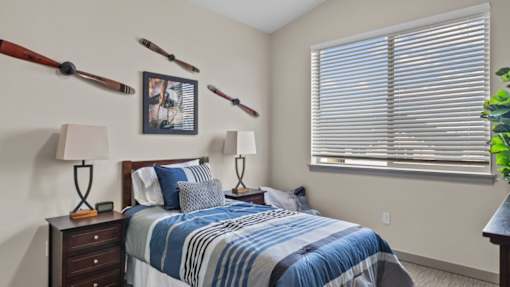 A bedroom with a bed, two lamps, and a picture on the wall.