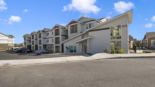 a row of apartment buildings with cars parked in front of them
