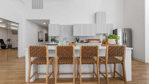 a kitchen with a long island with bar stools in front of a white counter