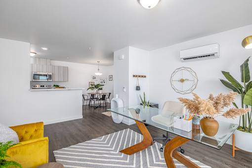 a living room with a glass table and a kitchen