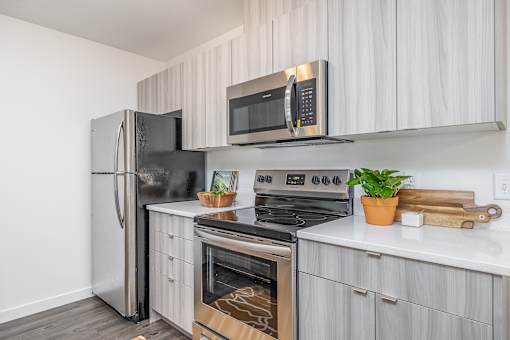 an apartment kitchen with stainless steel appliances and white cabinets