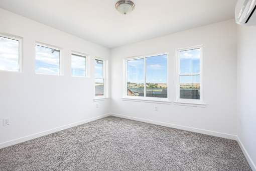 an empty room with four windows and a carpet