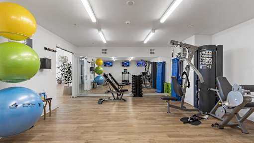 a gym with cardio equipment and weights on a wooden floor