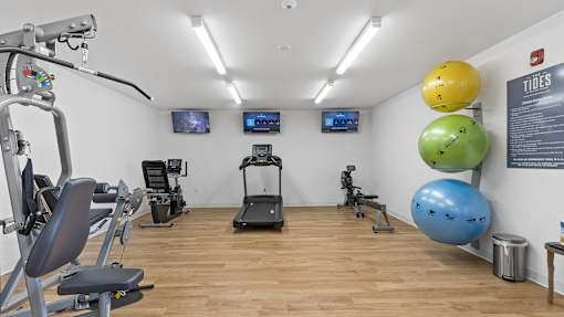 a gym with treadmills and other exercise equipment on a wood floor
