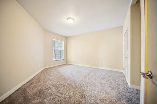 A room with a carpeted floor and a door on the right side.