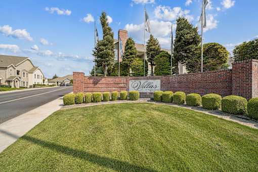A brick wall with a sign that says "Oakland" in front of a grassy area.