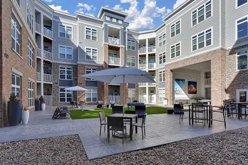 A patio with a table and chairs is surrounded by apartment buildings.