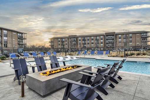 A fire pit sits in the middle of a pool surrounded by chairs.