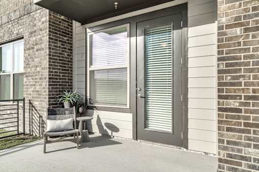 A patio with a chair and a potted plant.