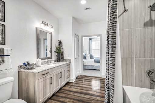 A bathroom with a white toilet, a wooden vanity, and a shower with a curtain.
