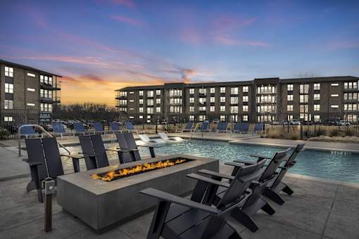 A poolside area with chairs and a fire pit in front of a building.