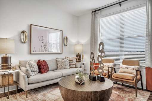 A living room with a grey couch, a wooden coffee table, and a painting on the wall.