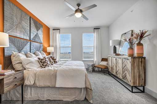 A bedroom with a large bed, a wooden dresser, and a ceiling fan.