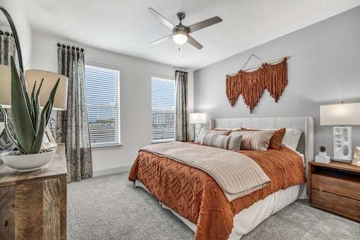 A bedroom with a bed, a ceiling fan, and a wooden nightstand.