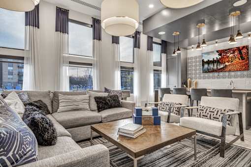 A modern living room with a grey sofa, a wooden coffee table, and a large painting on the wall.