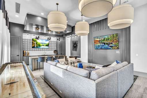 A modern living room with a grey couch and a pool table.