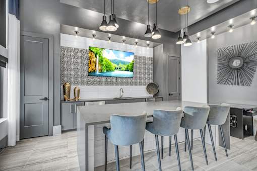 A modern kitchen with a large island and chairs.