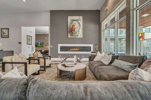 A modern living room with a grey couch and a fireplace.