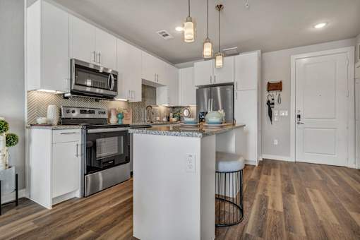 A modern kitchen with white cabinets and a wooden floor.