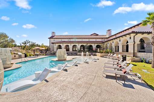 A pool area with sun loungers and a building in the background.
