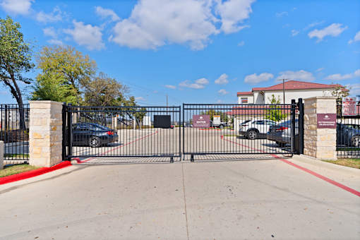 A black gate with a red stripe on the side blocks the entrance to a driveway.