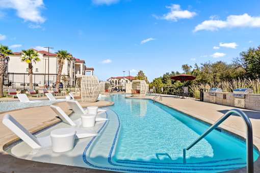 A large swimming pool with a slide and sun loungers.