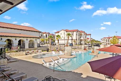 A pool area with a fountain and a building in the background.