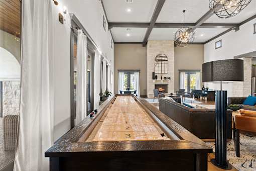 A long wooden table is in the middle of a room with a shiny floor.