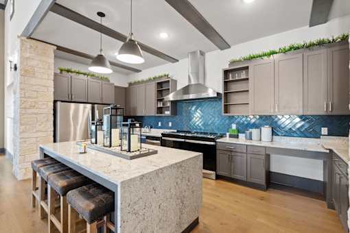 A kitchen with a marble island and a blue backsplash.