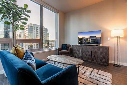 A blue chair is in front of a large window in a room with a flat screen TV.