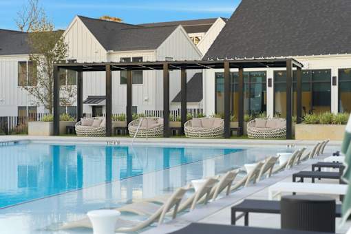 A pool with chairs and a building in the background.