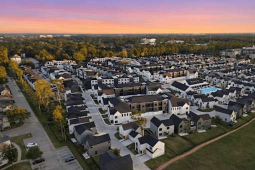 A sunset view of a residential area with houses and a pool.