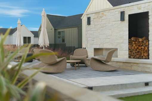 A patio with chairs and umbrellas is in front of a house.