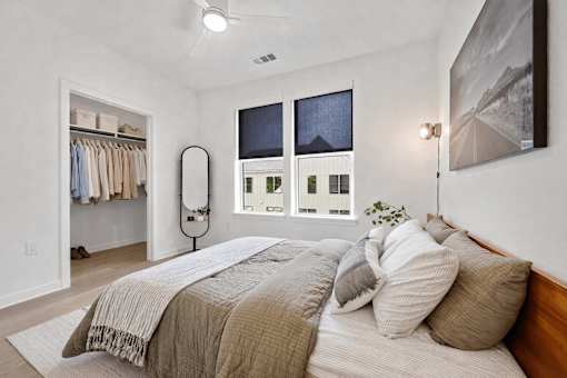 A bedroom with a large bed and a window with a view of a cityscape.