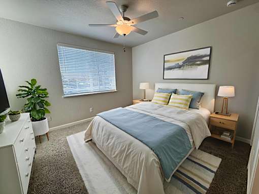 A bedroom with a bed, nightstand, and a ceiling fan.